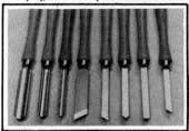 El juego de herramientas para el torno incluye (izquierda a derecha): tres gubias, dos cuchillas de filo oblicuo, una cuchilla de punta de lanza, la cuchilla de punta redonda y una fresa partidora
