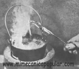 6. Con unas tenazas, saque la pieza del baño de cinc y agítela para eliminar el metal excedente. El humo que se ve se debe a la reacción de la sal amoníaco
